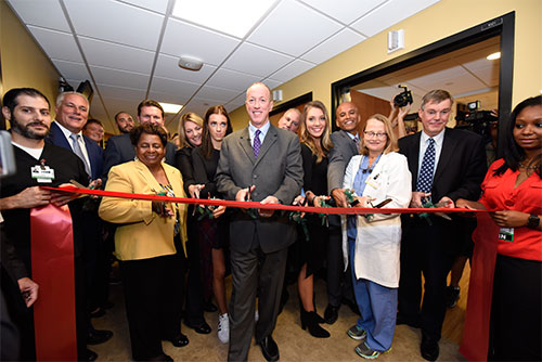 Jim and Jill Kelly, daughters Camryn and Erin (center) and other family members are surrounded by physicians, ECMCC board members including board chair Sharon Hanson (front row, third from left) and ECMCC Pres. & CEO Tom Quatroche (second row, behind Hanson) and other administrators as they cut the ribbon during the "Kelly Tough Room" dedication at ECMC on October 18, 2016.